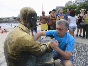 Voluntário limpa estátua de Drummond. (Foto: Maíra Coelho/Agência O Dia/Estadão Conteúdo)