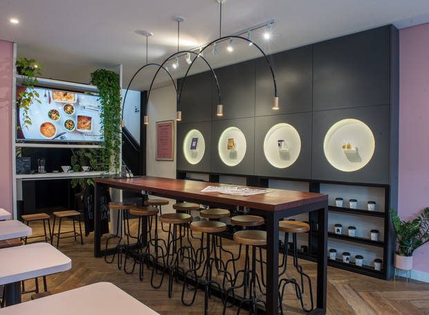 O Orna Café, em Curitiba, tem a decoração inspirada na arquitetura da cidade. O design minimalista tem pontos de cor com as plantas (Foto: Divulgação)