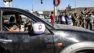 Israelense passa por manifestação de palestinos e ativistas da paz israelenses contra a expansão de assentamentos, na cidade ocupada de Salfit, na Cisjordânia  — Foto: JAAFAR ASHTIYEH / AFP
