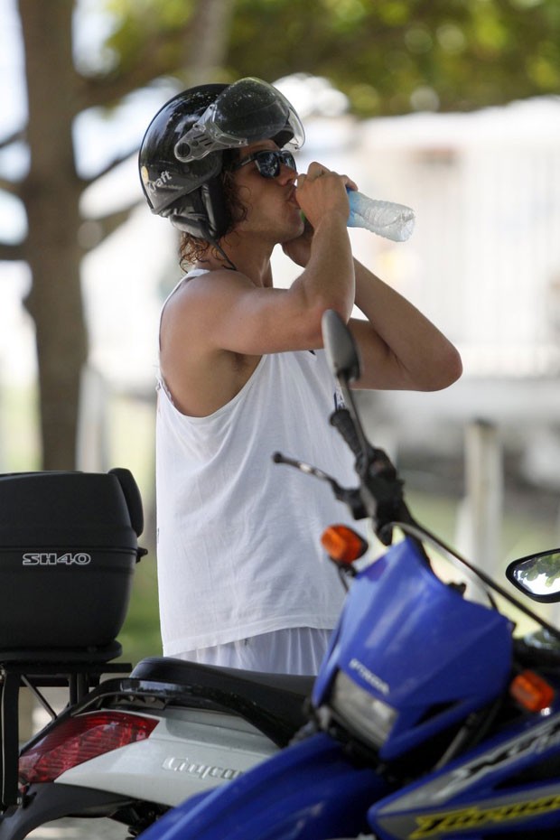 O ator se refresca tomando uma água antes de sair da praia (Foto: Foto Rio News)