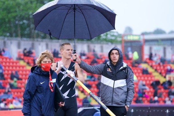 Sam Kendricks se prepara para saltar, mientras Armand Duplantis sostiene el paraguas - Foto: Matthew Quine / Disclosure