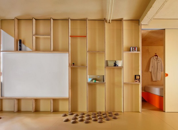 Um painel de madeira forma a divisória entre a sala e o quarto, que fica separado por uma porta de correr (Foto: José Hevia./ Dezeen)