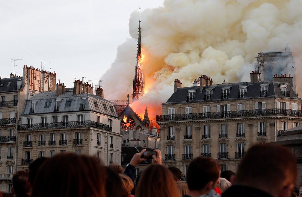 Pessoas observam de longe o grande incêndio que consome a Catedral de Notre-Dame, em Paris — Foto: Benoit Tessier/Reuters