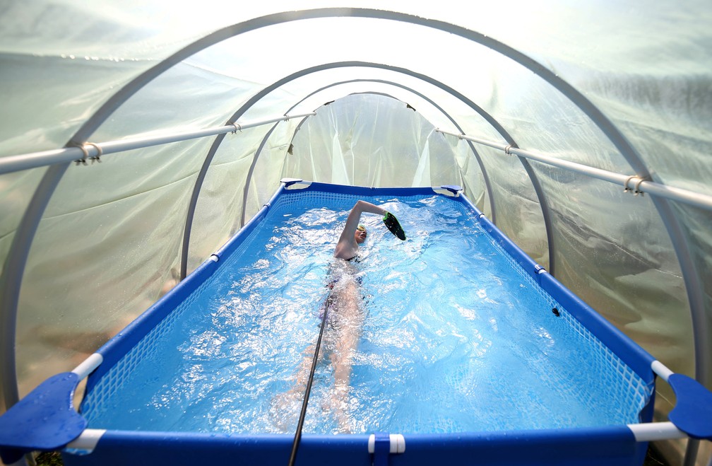 A nadadora Iman Avdic mantém sua forma praticando em uma pequena piscina de plástico dentro de uma estufa improvisada no pomar de seu avô em Doboj, na Bósnia e Herzegovina  — Foto: Dado Ruvic/Reuters