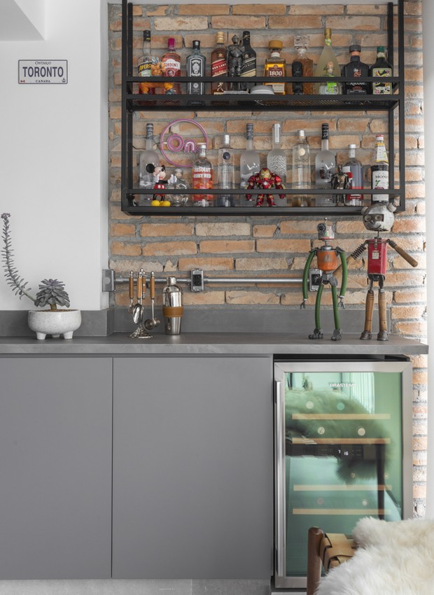 BAR | A bancada que vem da cozinha forma um bar na varanda, com armários executados pela Marcenaria Rami e estante suspensa preta feita por serralheria (Foto: Thiago Travesso/Divulgação)