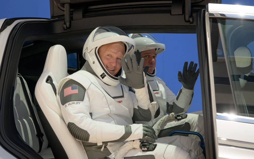 Os astronautas da NASA Douglas Hurley (esquerda) e Robert Behnken, usando trajes espaciais da SpaceX, acenam durante prova dos trajes dias antes do lançamento de sua missão, em Cabo Canaveral, na Flórida, no sábado (23) — Foto: Bill Ingalls/NASA via AP