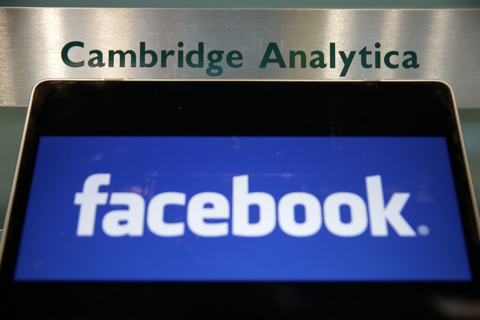 Logotipo do Facebook em frente a letreiro do prédio da Cambridge Analytica, empresa londrina que fechou depois de envolvida num escândalo global de quebra de privacidade (Foto: Daniel Leal-Olivas/France Presse)