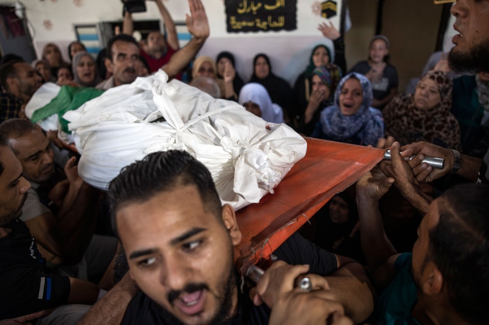 Corpo do militante do Hamas, Mohammad Abu Namous, Ã© carregado durante funeral no norte da Faixa de Gaza, neste domingo (18)  â€” Foto: Khalil Hamra/AP
