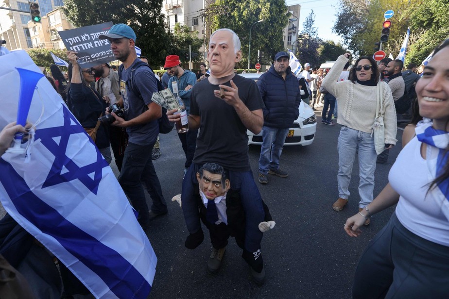 Um homem vestido com uma máscara do primeiro-ministro Benjamin Netanyahu enquanto israelenses protestam contra o controverso projeto de lei de reforma judicial do governo em Tel Aviv