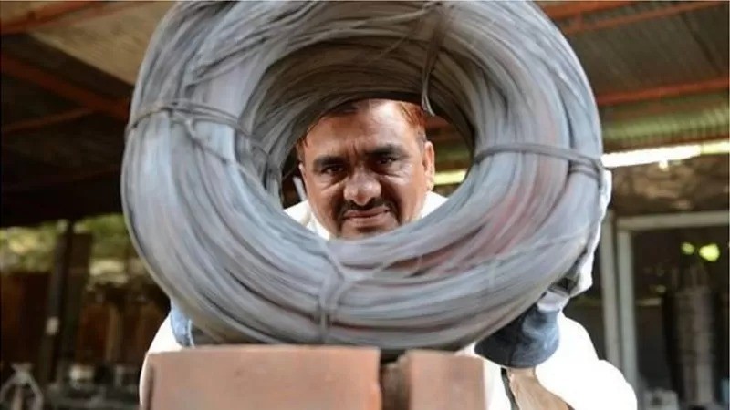 Niyazahmed Shaikh examina cuidadosamente rolos de fios produzidos com sucata de tiras de aço na sua fábrica na Índia (Foto: Getty Images )