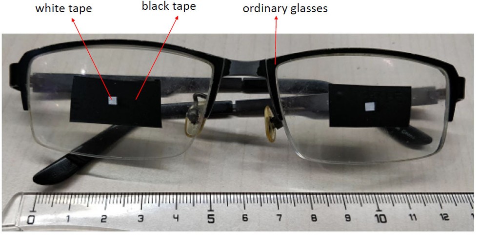 Protótipo de óculos criado por especialistas da Tencent. Ponto branco no centro, formado por fitas adesivas pretas e brancas, engana o FaceID. — Foto: Tencent