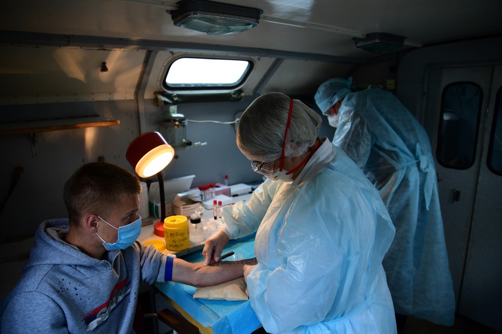 Agente de saúde tira amostra de sangue de recruta militar para teste rápido de Covid-19 na cidade de Vladivostok, no extremo leste da Rússia, no dia 4 de junho. — Foto: Pavel Korolyov / AFP