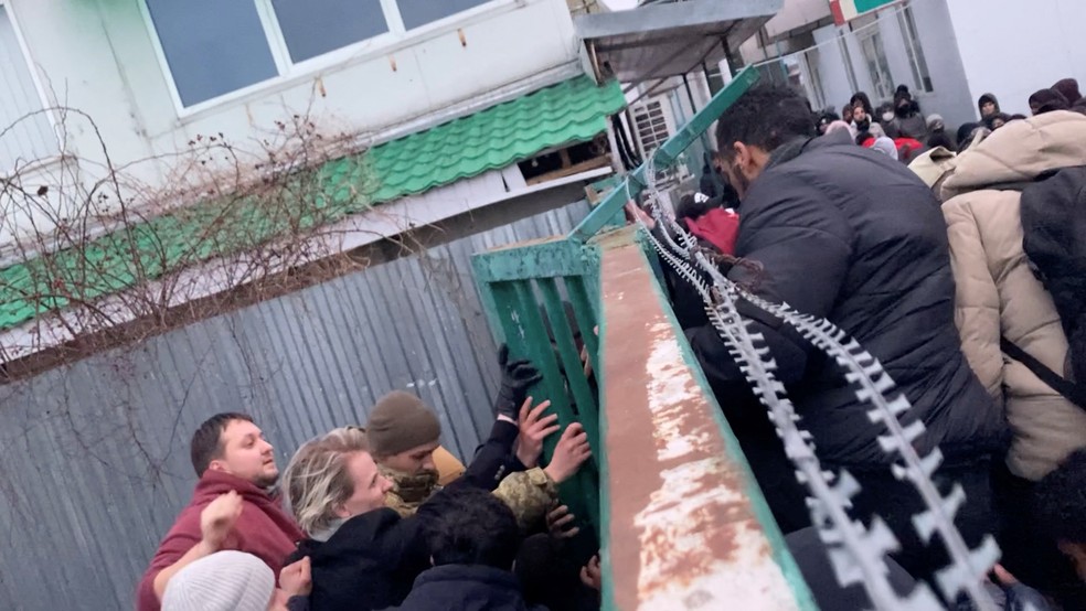 Refugiados ucranianos empurram portão na fronteira para entrar na Polônia — Foto: Reuters