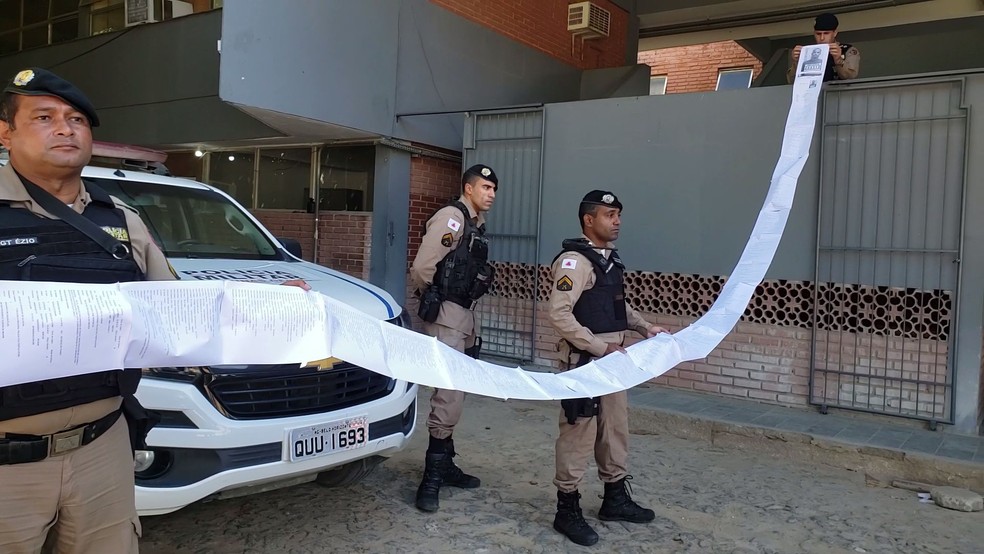 Policiais militares seguram ficha criminal de suspeito preso em Teófilo Otoni — Foto: Victor Duarte/Inter TV dos Vales