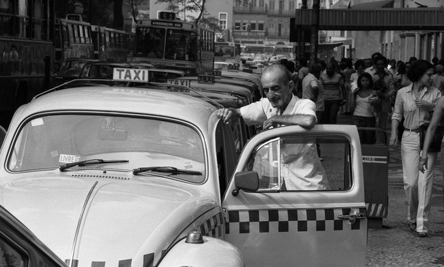Fusca. Motorista de táxi parado no Centro do Rio após aumento das tarifas, em 1980