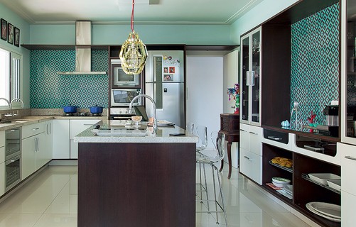 Azulejos retrô esverdeados revestem a cozinha projetada pela arquiteta Andrea Murao. A cor está presente em outras partes da decoração, como o sofá e a porta de correr