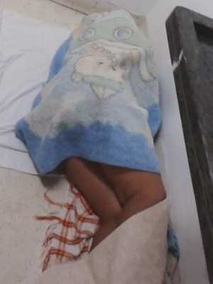 Mãe dorme em chão de hospital à espera de vaga em UTI para o filho, em Goiânia, Goiás (Foto: Reprodução/ TV Anhanguera)