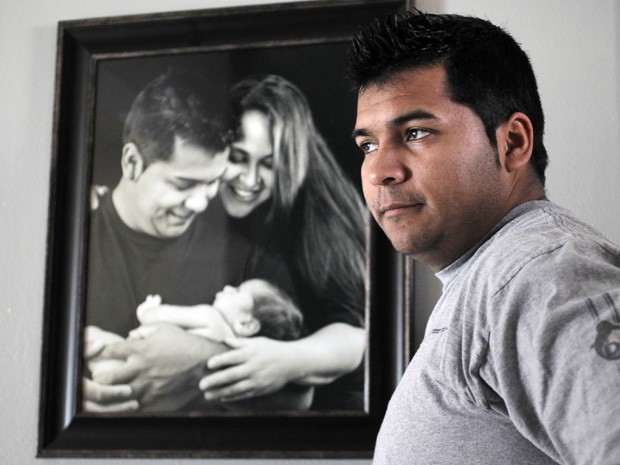 Erick Munoz aparece em frente a retrato dele com a esposa e com o filho do casal, Mateo (Foto: Ron T. Ennis/The Fort Worth Star-Telegram/AP)