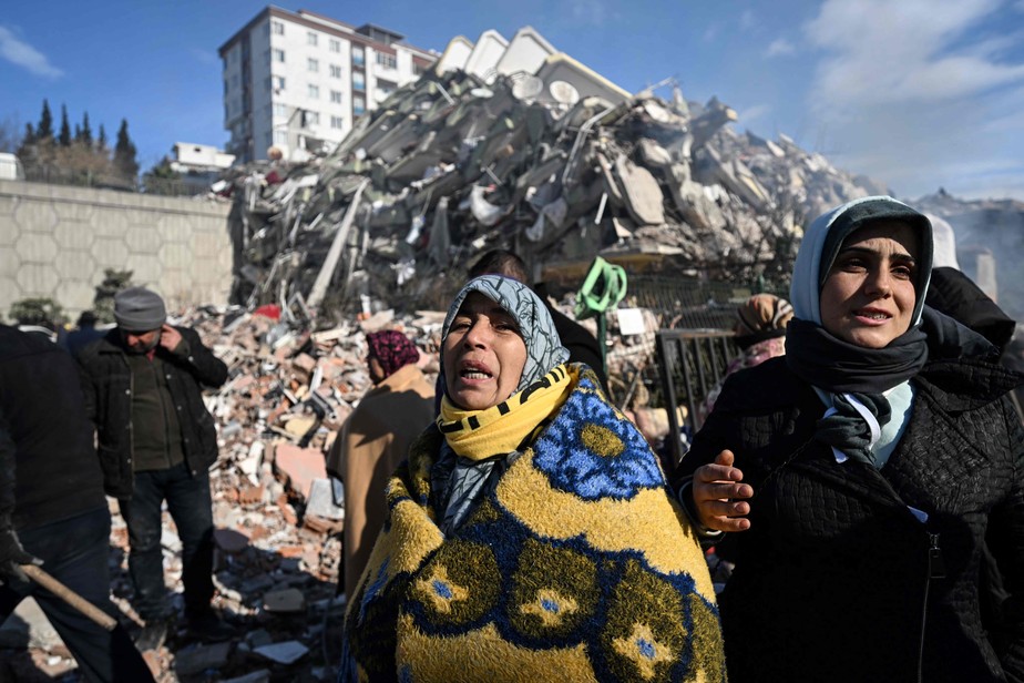 Mulheres aguardam equipe de resgate ao lado de seu prédio desabado na cidade de Kahramanmaras, no sudeste da Turquia, em 8 de fevereiro de 2023, dois dias após um forte terremoto atingir a região