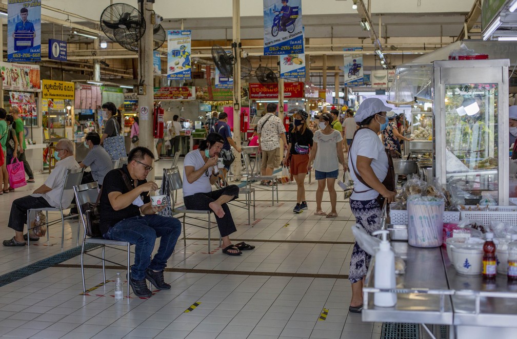 3 de maio: pessoas fazem distanciamento social enquanto comem em um mercado de Bangkok, na Tailândia, depois que as medidas de restrição para conter a Covid-19 foram relaxadas. — Foto: Gemunu Amarasinghe/AP