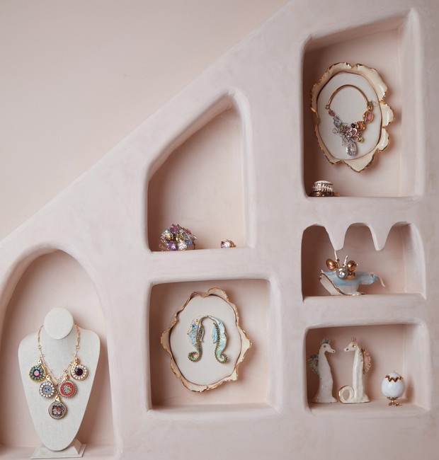 Colares, brincos e peças de cerâmica são exibidos dentro de pequenos nichos que foram cortados em estantes esculpidas em todo o espaço (Foto: Reprodução/Dezeen)
