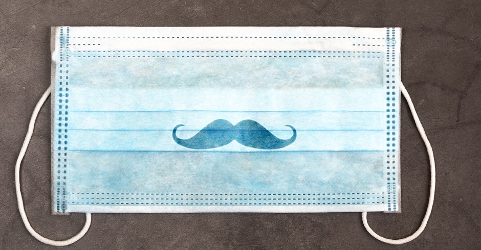 A medical mask with a drawn mustache. A typical surgical mask to cover the mouth and nose. Concept of protection against various viruses, including coronavirus and bacteria. Background grey plaster. (Foto: Getty Images/iStockphoto)