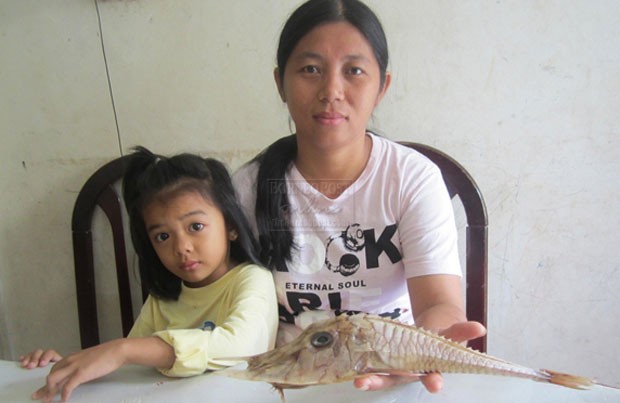  Siti Kadariah segura o peixe fisgado por seu marido (Foto: Reprodução/Facebook/BorneoPost)