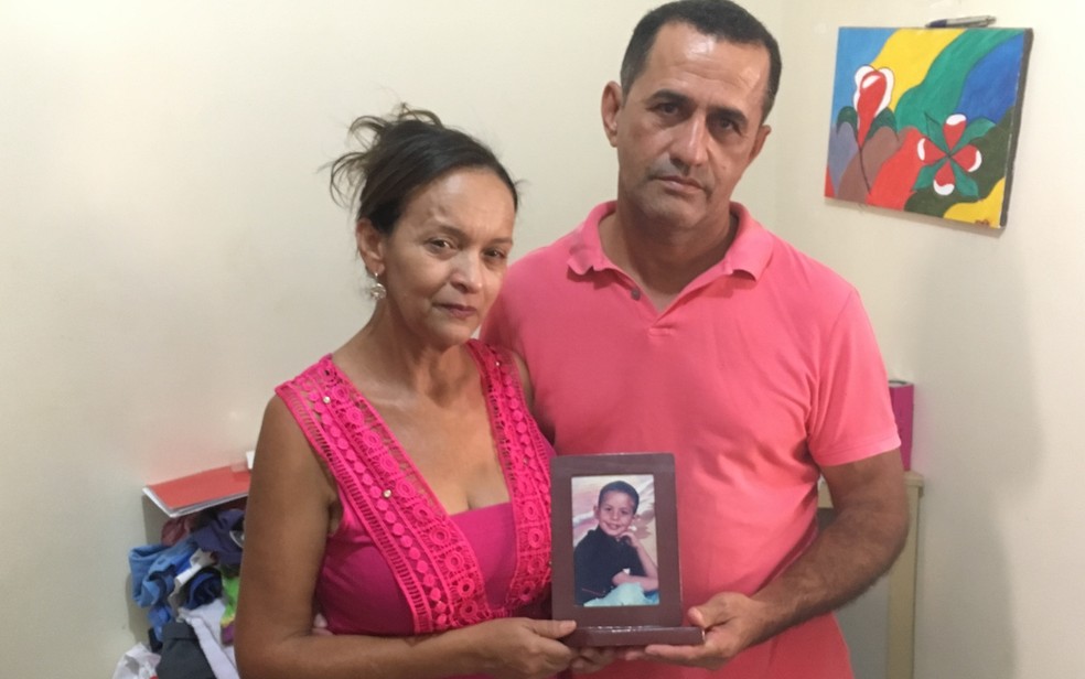 Idalira e o marido, Silvânio de Jesus, olham fotos do filho para aliviar a saudade  (Foto: Paula Resende/ G1)