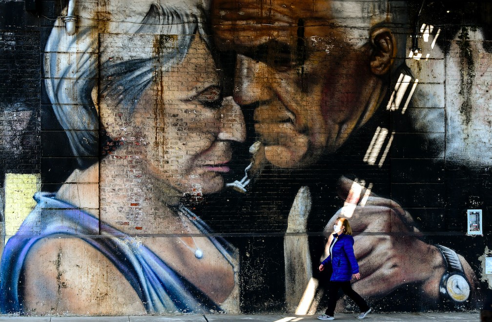 Mulher caminha em frente a um mural com a imagem de um casal dançando tango, em Buenos Aires, em 24 de agosto de 2020. — Foto: Ronaldo Schemidt/AFP