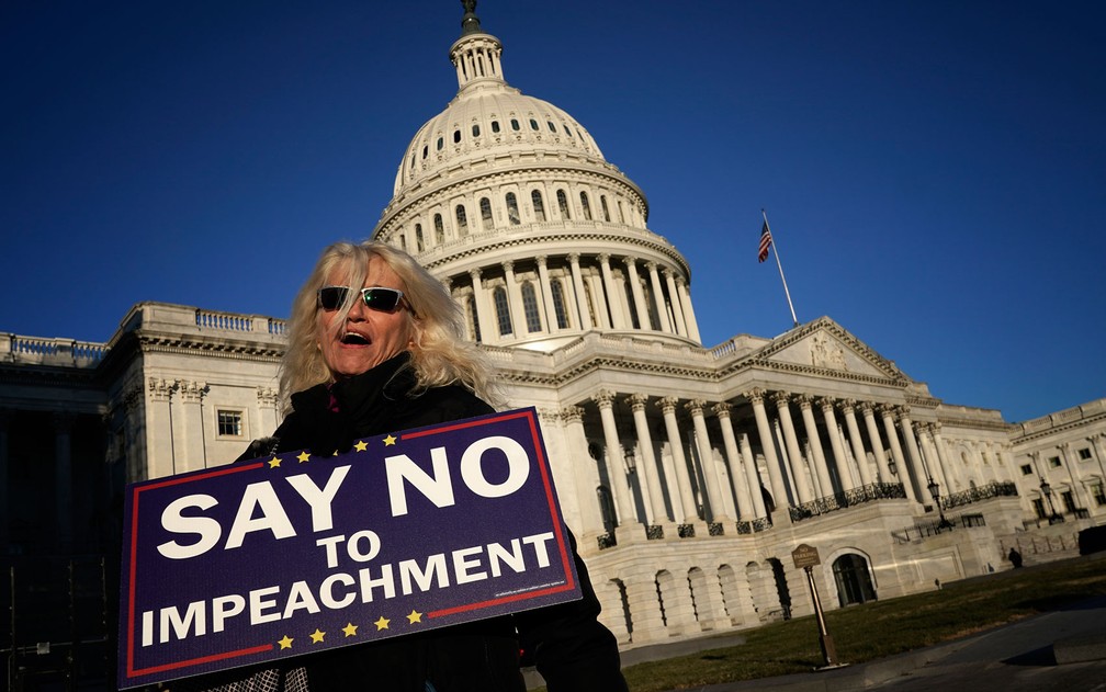 Apoiadora do presidente Donald Trump exibe cartaz contra o impeachment, em frente ao Capitólio, em Washington, na quarta-feira (18) — Foto: Win McNamee/Getty Images/AFP