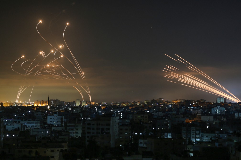 13 de maio - À esquerda, o poderoso sistema israelense de interceptação de mísseis, chamado Domo de Ferro. À direita, os foguetes lançados contra Israel pela milícia palestina Hamas, partindo de Beit Lahia, no norte da Faixa de Gaza — Foto: Anas Baba/AFP