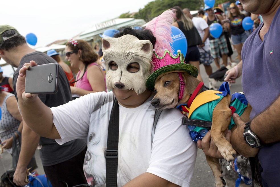 Mulher tira selfie com cachorro fantasiado em bloco para animais no Rio (Foto: Silvia Izquierdo/AP)