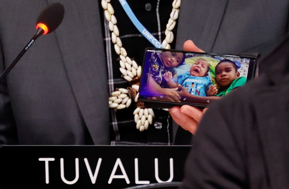  Seve Paeniu, ministro de Tuvalu, mostra fotos de seus netos na COP26 — Foto: Phil Noble/Reuters