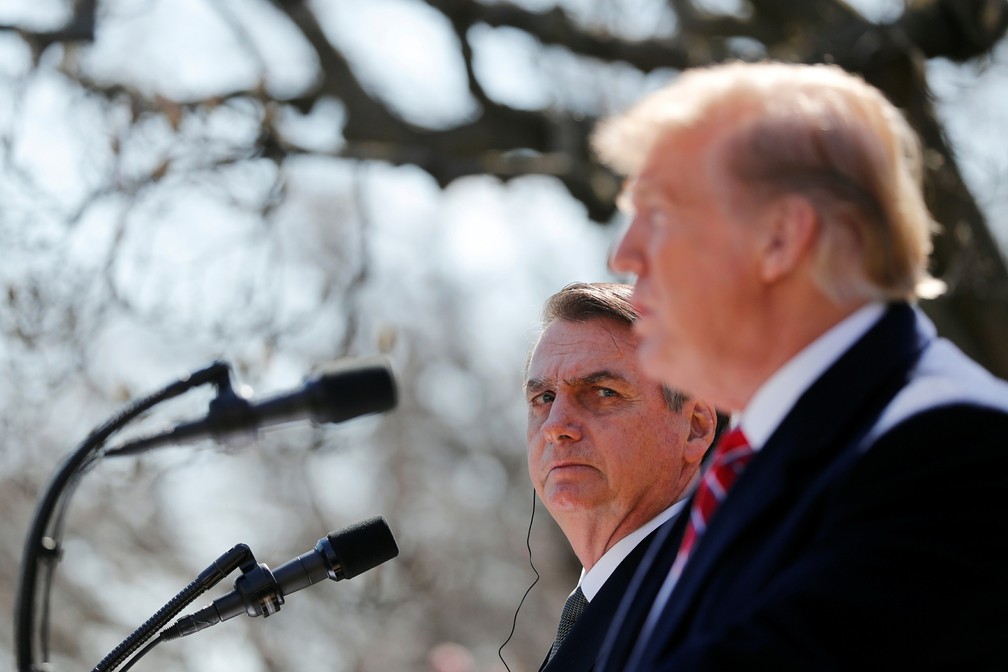 19 de março - O presidente Jair Bolsonaro observa enquanto o presidente dos EUA, Donald Trump, fala em entrevista coletiva na Casa Branca após reunião em Washington — Foto: Carlos Barria/Reuters