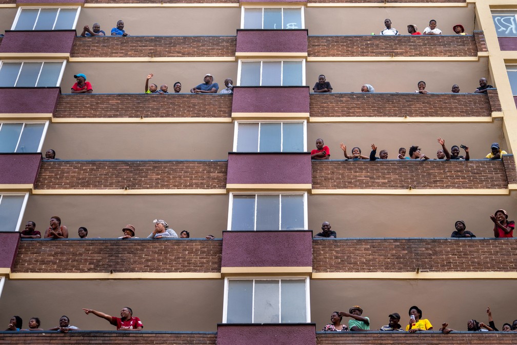 Moradores do povoado de Hillbrow, no centro de Joanesburgo, na África do Sul, acenam de suas varandas durante isolamento para impedir que o coronavírus se espalhe — Foto:  Jerome Delay/AP