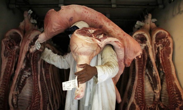 Trabalhador carrega pedaços de carne em açougue em São Paulo  