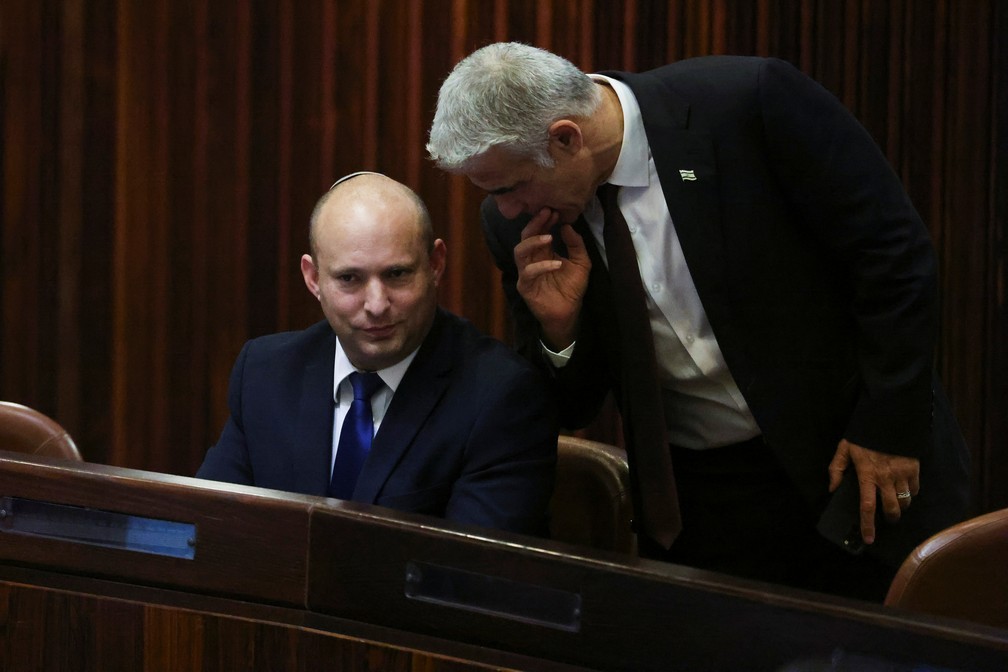 Sentado, Naftali Bennett fala com Yair Lapid durante sessão no Parlamento Israelense nesta quarta (2). Os dois devem se revezar no comando do governo de Israel, caso os parlamentares ratifiquem a coalizão — Foto: Ronen Zvulun/Reuters