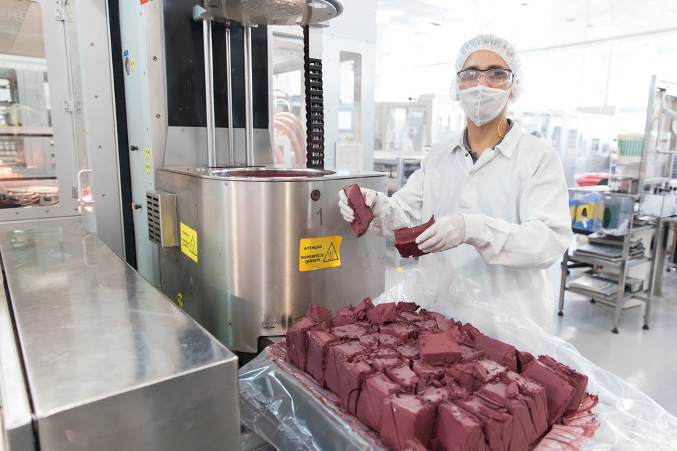 Operário corta barra de batom em pedaços para inseri-los na máquina (Foto: Celso Tavares/G1)