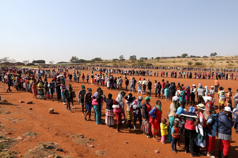20 de maio - Pessoas fazem em uma fila para receber ajuda alimentar durante pandemia de Covid-19 no assentamento informal Itireleng, próximo ao subúrbio de Laudium, em Pretória, na África do Sul   — Foto: Siphiwe Sibeko/Reuters