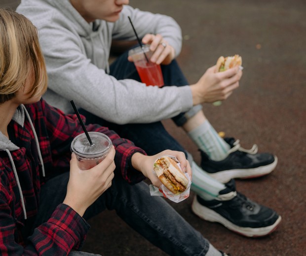 Imagem ilustrativa de adolescentes comendo hambúrguer (Foto: Pexels)