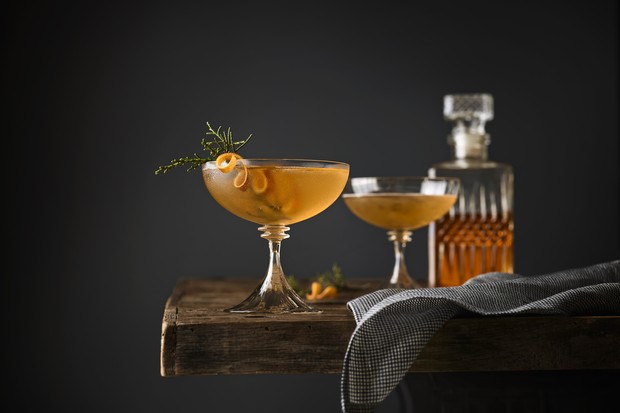 Still life of two Manhattan cocktails garnished with Juniper on a table with whiskey decanter in the background. (Foto: Getty Images)