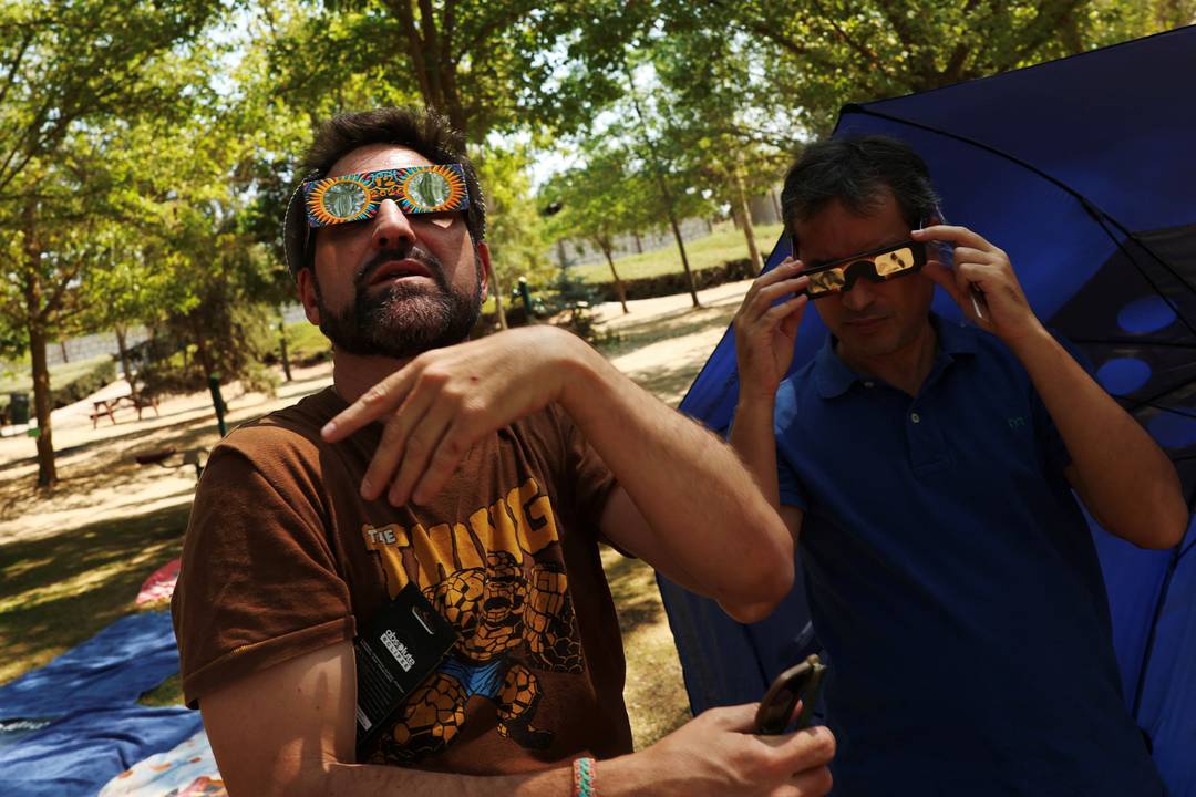 Cesar Berzal e o amigo Pablo Corazon experimentam óculos de proteção durante um evento para acompanhar o eclipse solar total em Buitrago del Lozoya, na Espanha, nesta quarta-feira (12).