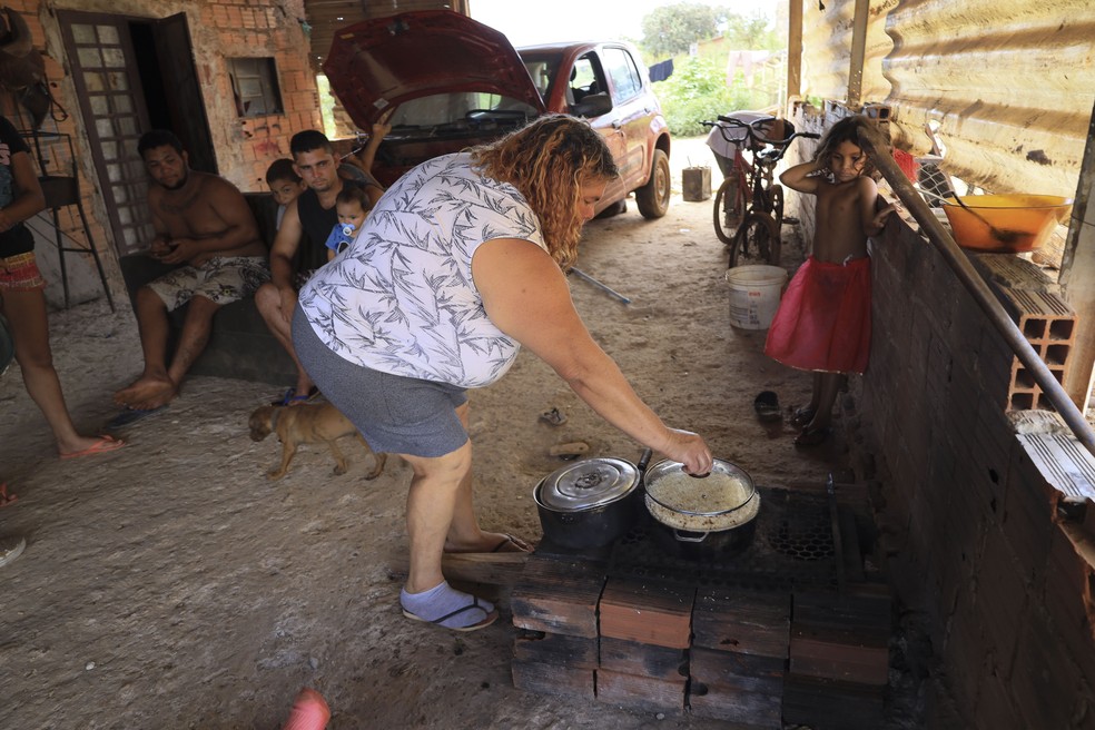  Família cozinha num fogareiro no chão: mesmo sem serviços público essenciais, famílias dizem que Sol Nascente não é favela  — Foto: Fernando Donasci