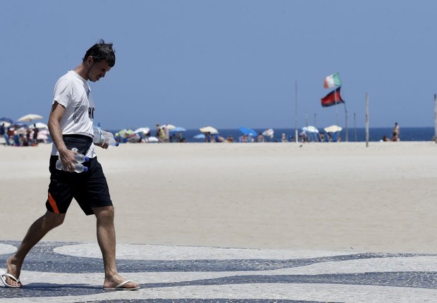 Homem anda no calçadão do Rio com garrafas de água gelada nas mãos (Foto: Tânia Rêgo/Agência Brasil)