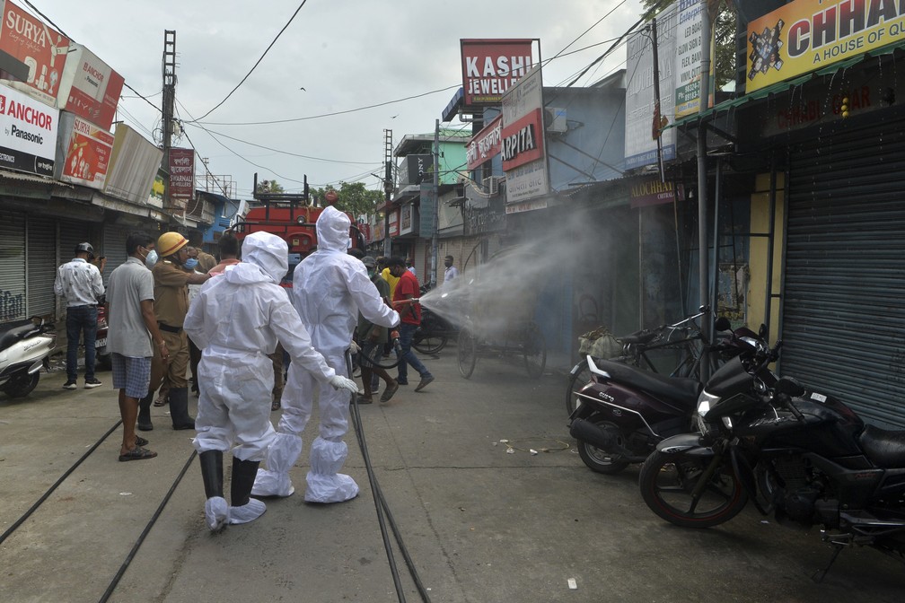 22 de junho: bombeiros usam spray desinfetante em lojas fechadas de um mercado em Shiliguri, na Índia, contra a Covid-19. — Foto: Diptendu Dutta / AFP