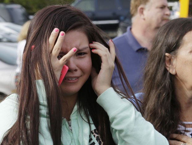 Jovem chora em igreja para onde parte dos alunos da escola foram levados (Foto: AP/Ted Warren)