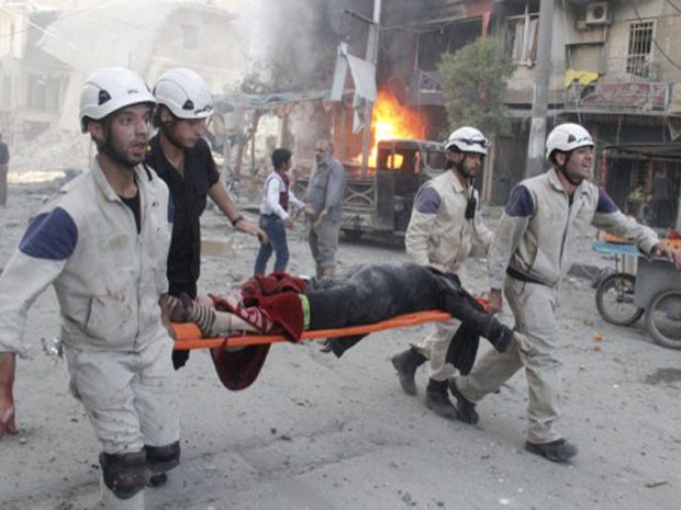 Socorristas ajudam no resgate de vítima de bombardeio em bairro de Aleppo, na Síria. Segundo ONG, ataque foi feito por militares pró-Assad (Foto: Khaled Khatib/Aleppo Media Centre/ AFP)