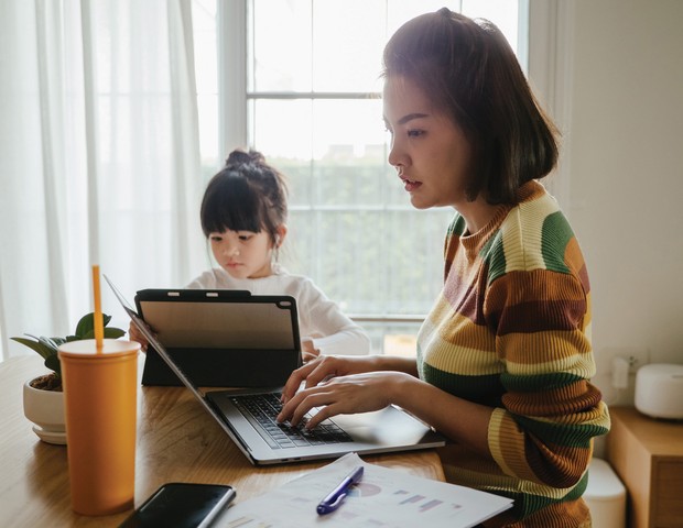 Asian mother and daughter using digital tablet and laptop together in living room at home. (Foto: Getty Images)