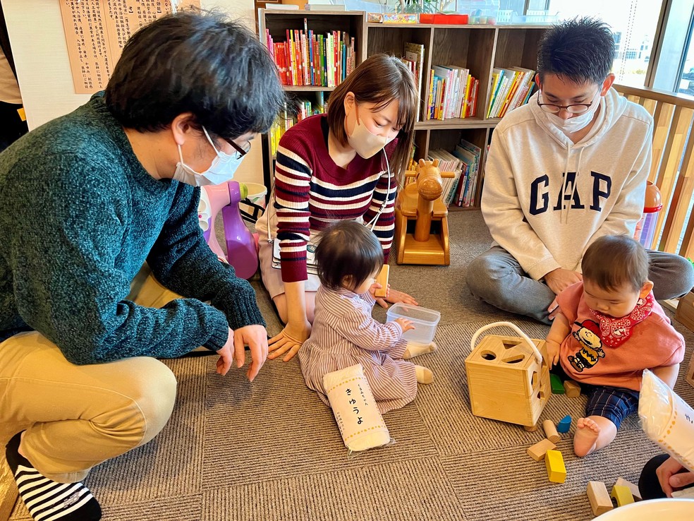 As pequenas Kurumi (à esquerda) e Rena brincam observadas pelos pais. No chão, no pacote de fralda está escrito “salário” em japonês  — Foto: Mariza Tavares 