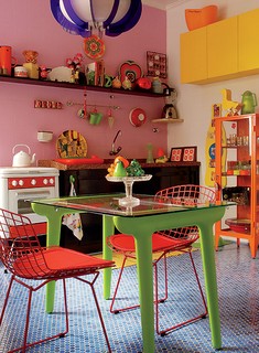 A cozinha original era bege. Mas no projeto do arquiteto Rodrigo Ângulo ganhou piso de pastilhas em vários tons de azul, parede rosa, armários amarelo-flúor e móvel e objetos muito coloridos